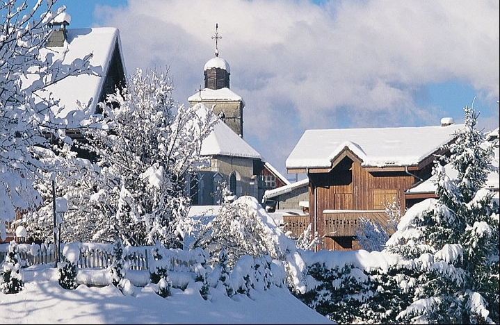 Snow-covered village houses and church in Morillon for Geneva to Morillon Transfers